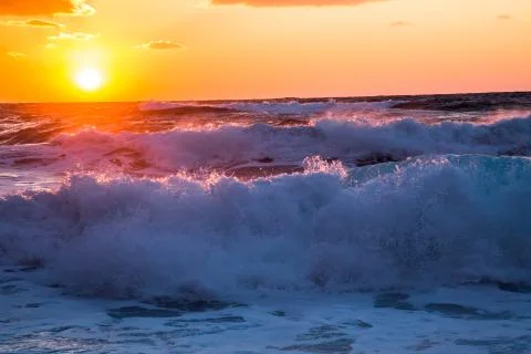 Breaking waves below bright vibrant sunset on the Sea of Japan Stock Photos