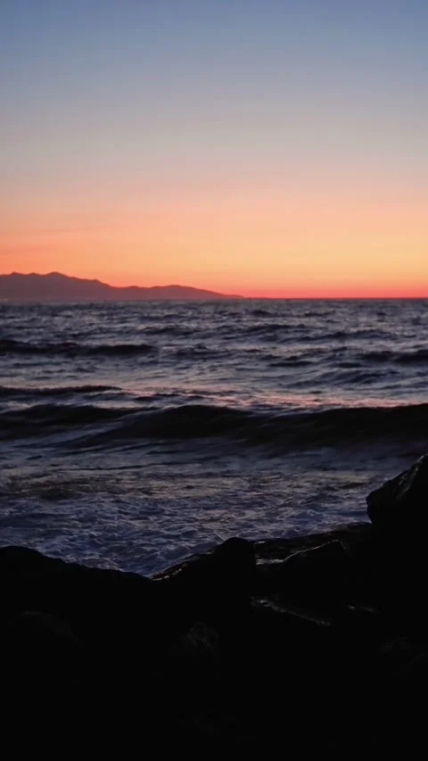 Breaking waves on rocks during beautiful sunset over calm ocean Stock Footage 310539654