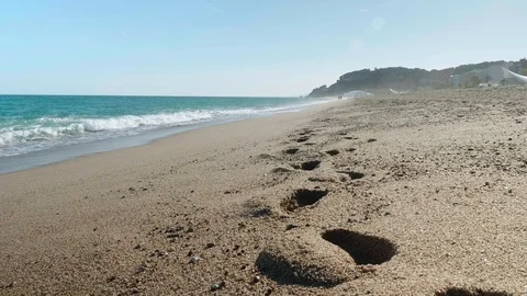 Breaking waves of sea. Unrecognizable people walking along sea. Traces on wet Stock Footage 116414294