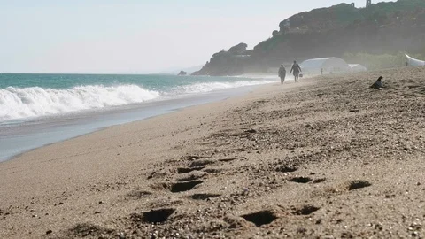 Breaking waves of sea. Unrecognizable people walking along sea. Traces on wet Stock Footage 116715818