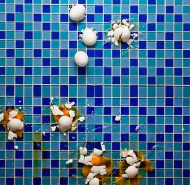 Breaking white eggs on a backsplash tiled surface in a kitchen Stock Photos