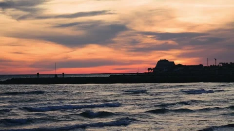 A breakwater against the backdrop of a beautiful sunset. Sea waves crash against Stock Footage 334138603