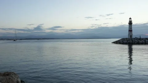 Breakwater and lighthouse with its reflection on the calm sea in the morning Video stock 56630472