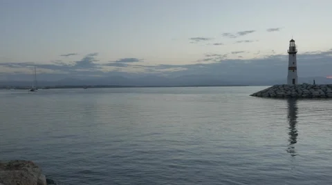 Breakwater and lighthouse with its reflection on the calm sea in the morning Stock Footage 56734991