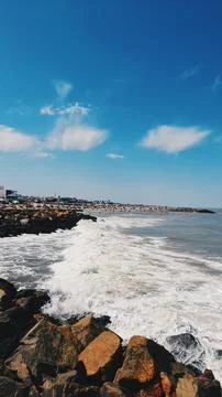 Breakwater, beach, rocks, sky with clouds, sea, waves Stock Photos