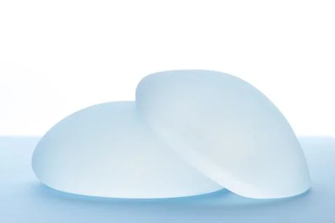 Breast implants on blue background. Copy space Stock Photos