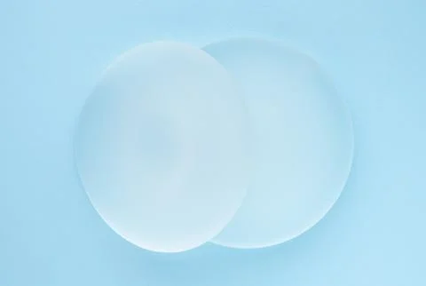 Breast implants on blue background. Top view Stock Photos