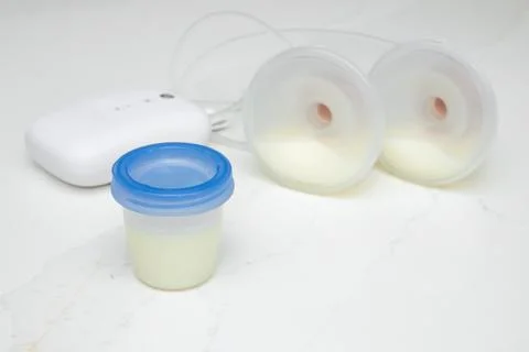 Breast milk in a storage container with a breast pump. Stock Photos