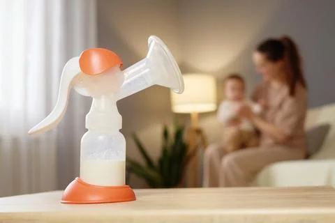 A breast pump is displayed on a table, while a mother interacts with her ba.. Stock Photos