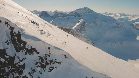Breathtaking aerial side shot of two skiers on a steep mountain slope Stock Footage 99739813