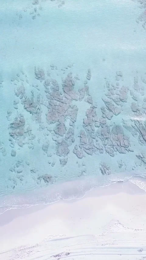 Breathtaking aerial top-down view of gentle waves lapping pristine white sand Stock Footage 344389361