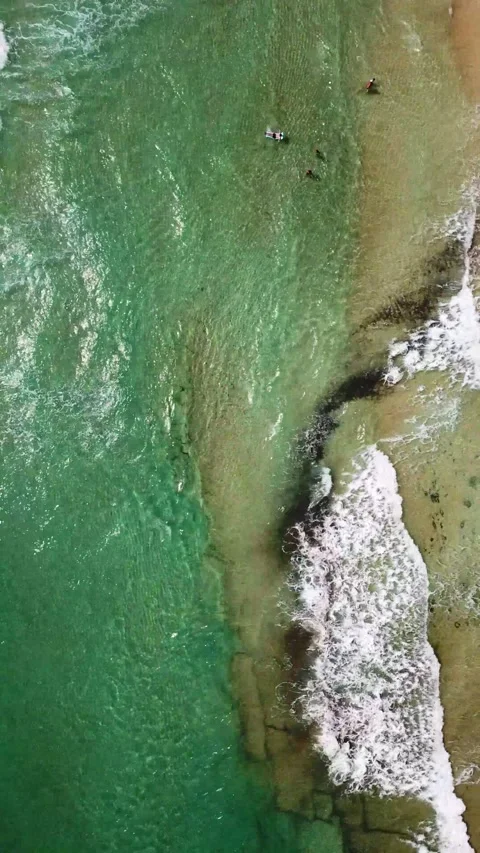 Breathtaking aerial top-down view of unrecognizable surfers paddling on their Stock Footage 344846384