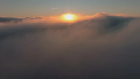 Breathtaking aerial view above a dense layer of clouds at sunset, with the sun 動画素材 335721148