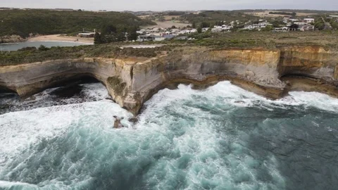 Breathtaking aerial view of ocean waves crashing against limestone cliffs near P Stock Footage 335980467