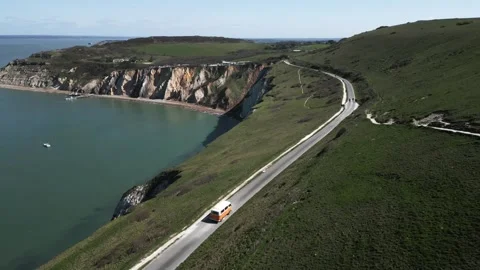 Breathtaking aerial view of a van on a hilly road along a mountainous coastline Stock Footage 247054840