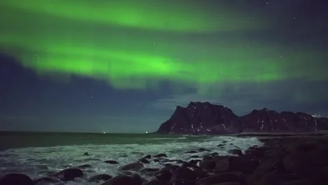 Breathtaking Aurora Borealis Dancing Over Rocky Beach and Majestic Peaks in Norw Stock Footage 308969966