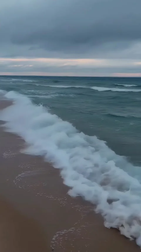 Breathtaking Ocean Waves Crashing on Sandy Shore at Sunset Video stock 303102718