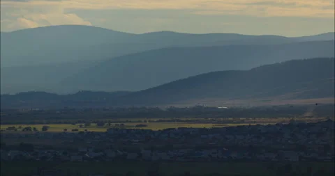 Breathtaking panoramic valley settlement with rolling hills and gentle haze 스톡 동영상 302584040