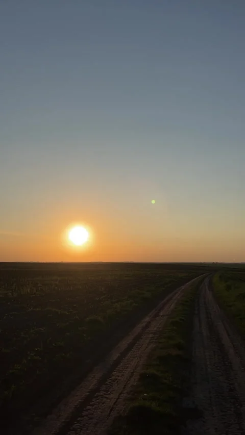 Breathtaking Serene Sunset Over a Charming Rural Road Surrounded by Vast Fields Stock Footage 306076712
