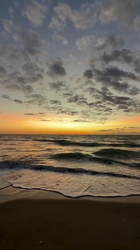Breathtaking sunset over the ocean with soft clouds and gentle waves washing Vidéo 334163253