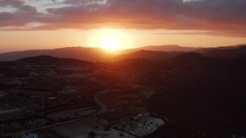A breathtaking sunset over rolling hills and mountains, with a winding road Stock Footage 309622791