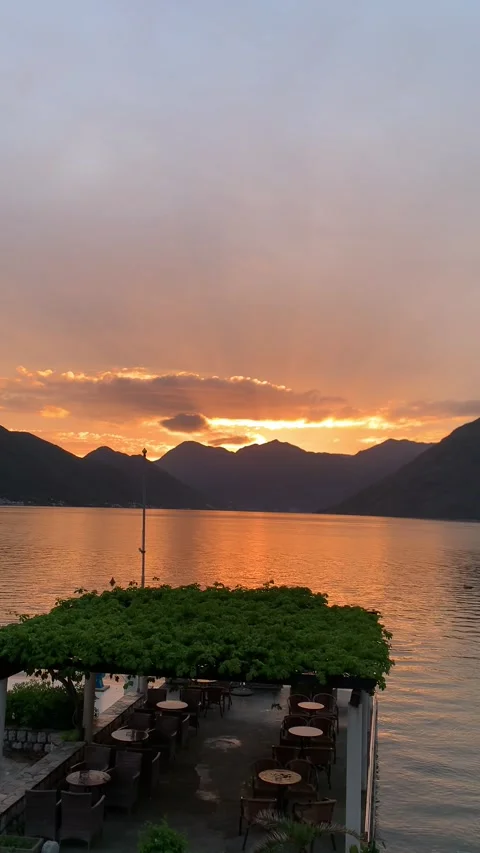 A breathtaking sunset over a serene lake surrounded by majestic mountains. The g Stock Footage 296284864