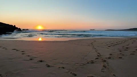 The Breathtaking Sunset Over the Tranquil Beach with gentle Waves crashing upon Stock Photos