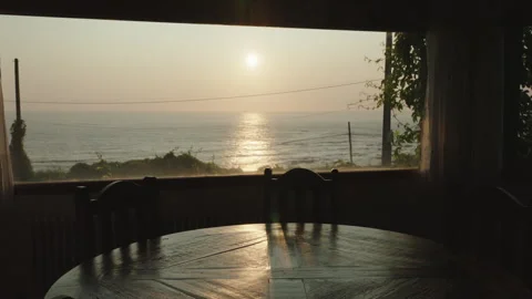 Breathtaking sunset view over the ocean framed by a dining room window, casting Видео 336203202