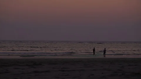 Breathtaking sunset at a wide beach with activity of walk, stroll, yoga Stock Footage 106067927