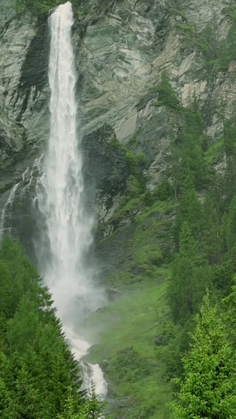 A breathtaking vertical video of a powerful waterfall cascading down a rugged Stockbeeldmateriaal 285472111