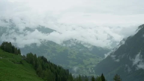 A breathtaking view of an alpine valley blanketed by clouds, revealing lush Stock Footage 282734854