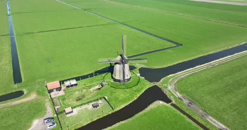 A breathtaking view of an ancient Dutch windmill, standing tall amidst the lush Vídeo Stock 237464771