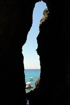 A breathtaking view of the endless sea opens up through the dark grotto. 스톡 사진