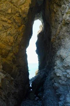 A breathtaking view of the endless sea opens up through the dark grotto. 스톡 사진
