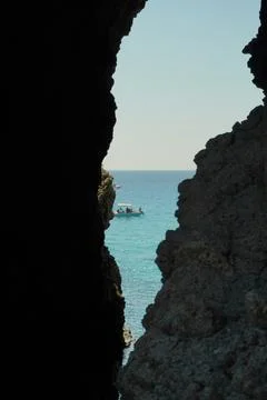 A breathtaking view of the endless sea opens up through the dark grotto. 스톡 사진