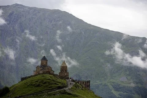 A breathtaking view of a mountain range with a ancient Gergeti Trinity Church Foto stock