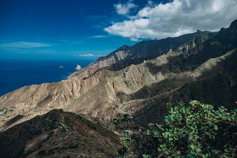 Breathtaking view of rugged mountains and deep blue ocean on a sunny day Stock Photos