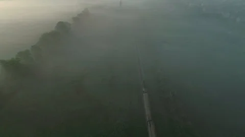 Breathtaking view of train rolls across foggy landscape at sunrise with ethereal Stock Footage 116480996