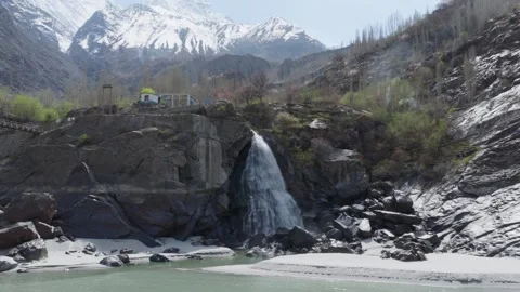 A breathtaking view of a waterfall cascading down a rocky cliff in the snowy 스톡 동영상 314455215