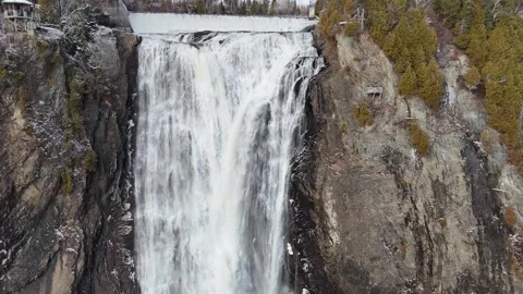 Breathtaking waterfall cascading down rugged rocky cliff surrounded by lush Видео 331607426