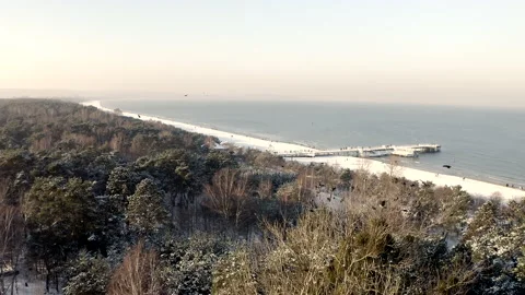 Breathtaking Winter Flight Above A Sandy Beach With Pier Full Of Walking People Stock Footage 150045095