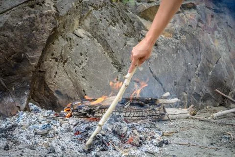 Breeding a fire on an old ashes on a sandy beach in the mountains Stock Photos