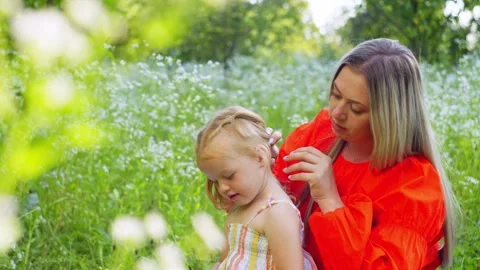 The breeze gently moves her daughter's hair as her mother straightens it. Stock Footage 252065307