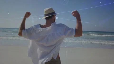 Breeze nudging man with hat stretching, turning, walking shore while blue over Video stock 330980450