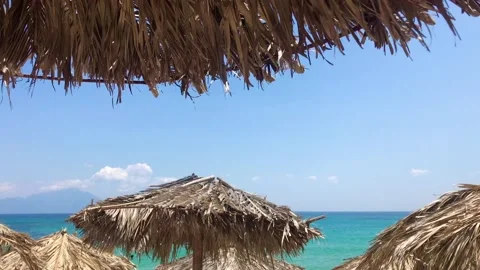 Breezy summer day under straw sun umbrellas and beachfront view on azure Stock Footage 135711487