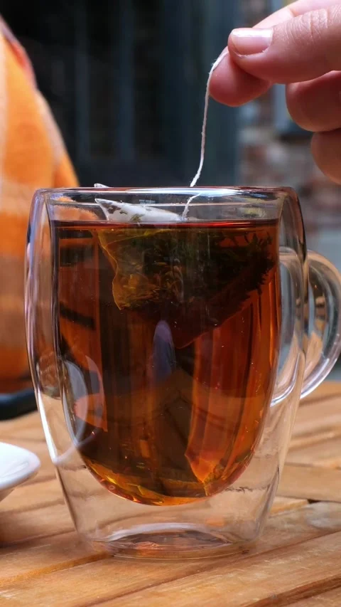 Brew a bag of black leaf tea in a clear mug with hot water. Warm up on a cool Stock Footage 318067664