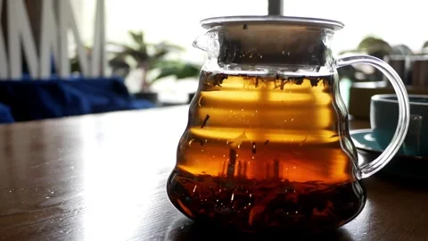 Brew tea in glass teapot. Making flower tea. Cafe, counter light. Brewed black t Stock Footage 274078835