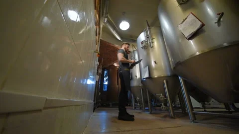 The brewer on the background of beer tanks makes calculations Stock-Footage 101427357
