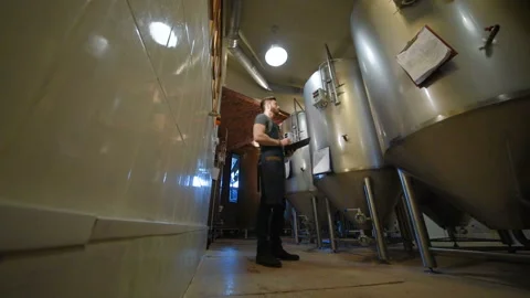 The brewer on the background of beer tanks makes calculations Stock-Footage 102794710