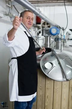 Brewer is controls the brewing process near reservoir with beer Stock Photos